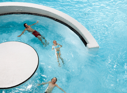 Drei Kinder lassen sich im Strudel in einem Becken der Therme Wien treiben.