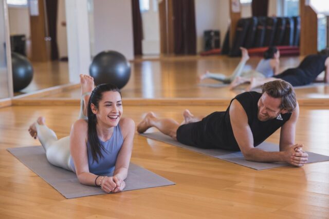 Frau und mann in der Therme wien fitness. Sie liegen auf einer Yogamatte und lachen.