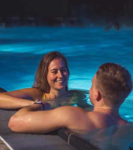 Junges paar liegt entspannt an einem Sommerabend outdoor in einem Becken der Therme Wien.