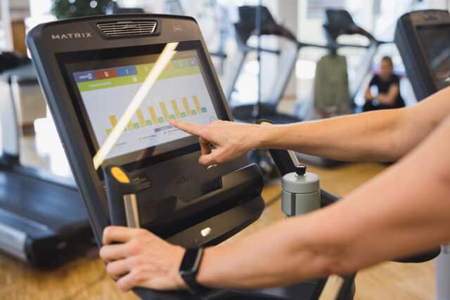 Cardiotraining in der Therme Wien Fitness. Frau gibt ihre Einstellungen in den Screen des Geraets ein.