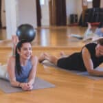 Junge Frau und und junger Mann liegen auf dem Bauch auf einer Yogamatte.