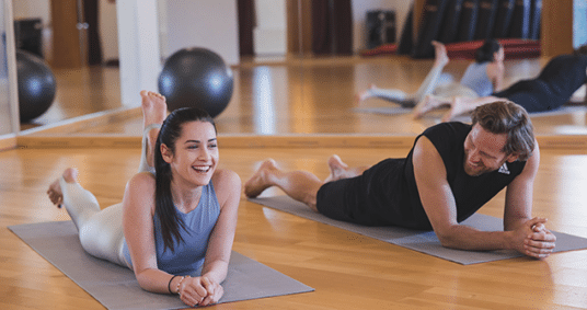 Junge Frau und und junger Mann liegen auf dem Bauch auf einer Yogamatte.