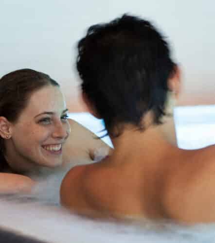 Junges Paar liegt entspannt in einem Becken der Therme Wien.