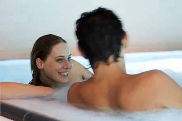 Junges Paar liegt entspannt in einem Becken der Therme Wien.