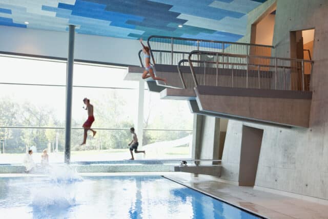 Kinder springen erheitert vom Sprungturm in der Therme Wien.