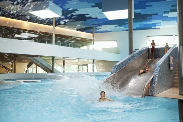 Kinder und Jugendliche rutschen erheitert auf Wasserrutsche in der Therme Wien.