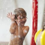 Kleiner Junge spielt im Springbrunnen im Kinderbereich der Therme Wien.