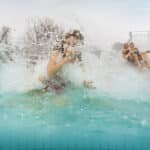 Tochter, Vater und Sohn rutschen eine Wasserrutsche hinunter im Aussenbereich der Therme Wien.