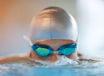 Mann mit Schwimmhaube und Schwimmbrille beim Schwimmen in der Therme Wien