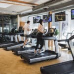 Frau und ein Mann laufen auf den Laufbaendern in der Therme Wien Fitness.