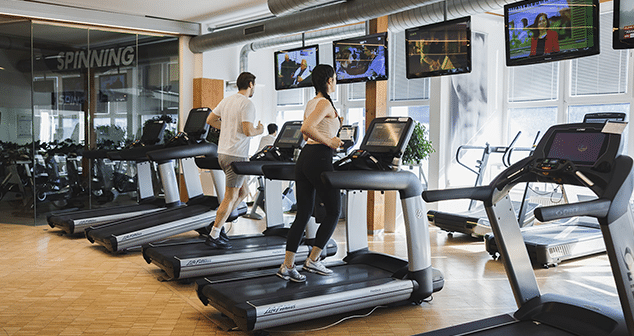 Frau und ein Mann laufen auf den Laufbaendern in der Therme Wien Fitness.