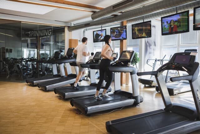 Frau und ein Mann laufen auf den Laufbaendern in der Therme Wien Fitness.