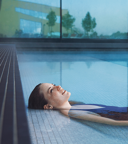 Frau liegt entspannt im Solebecken der Therme Wien.