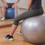 Frau sitzt am Gymnastikball und macht Uebungen fuer ihre Fitness.