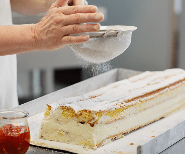 Kuchen wird mit Staubzucker bestreut für das Thermenrestaurant.