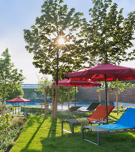 Sonnenliegen mit Schirm im Aussenbereich der Therme Wien.