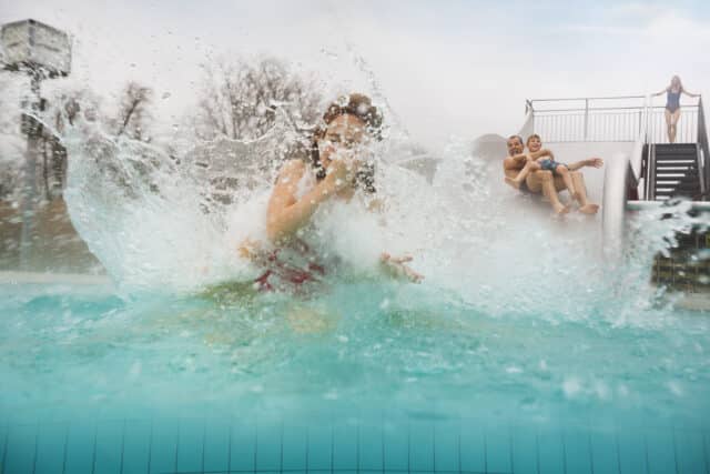 Vater Tocher und Sohn rutschen eine Wasserrutsche im Aussenbereich der Therme Wien herunter.