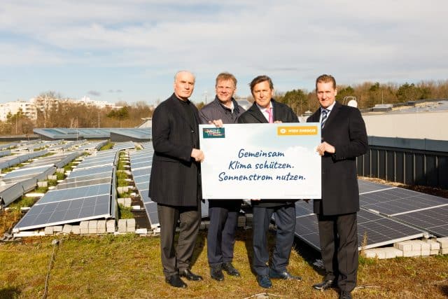 Vier Herren am Dach der Therme Wien. Im Hintergrund solarpaneele die am Dach montiert sind.