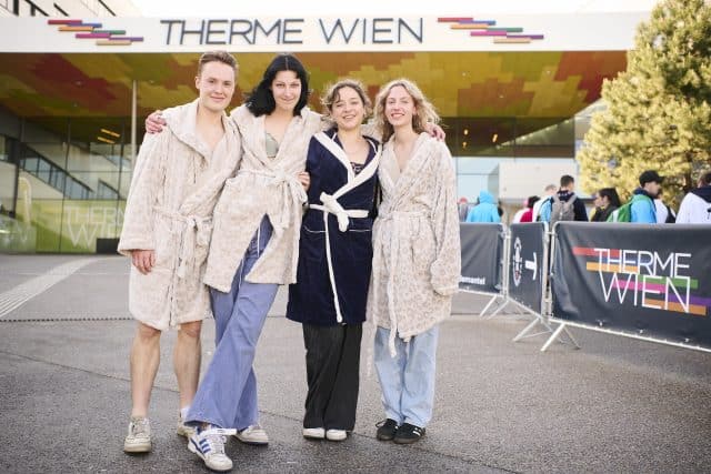 Drei Frauen und ein Mann posieren beim Wiener Bademanteltag der Therme Wien in Bademaenteln